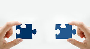zwei Hände, die jeweils ein Puzzleteil halten; Symbolbild für Workflow.